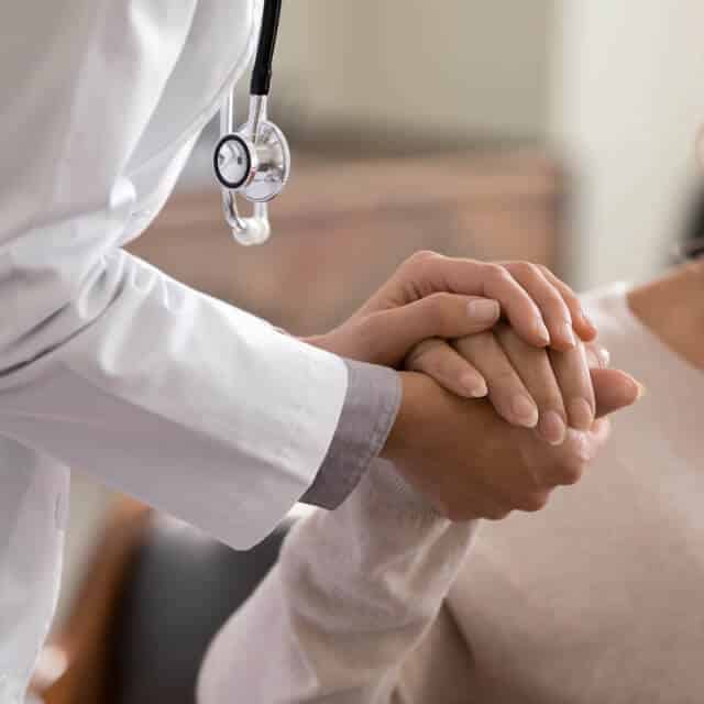 A doctor clasps a patient's hand