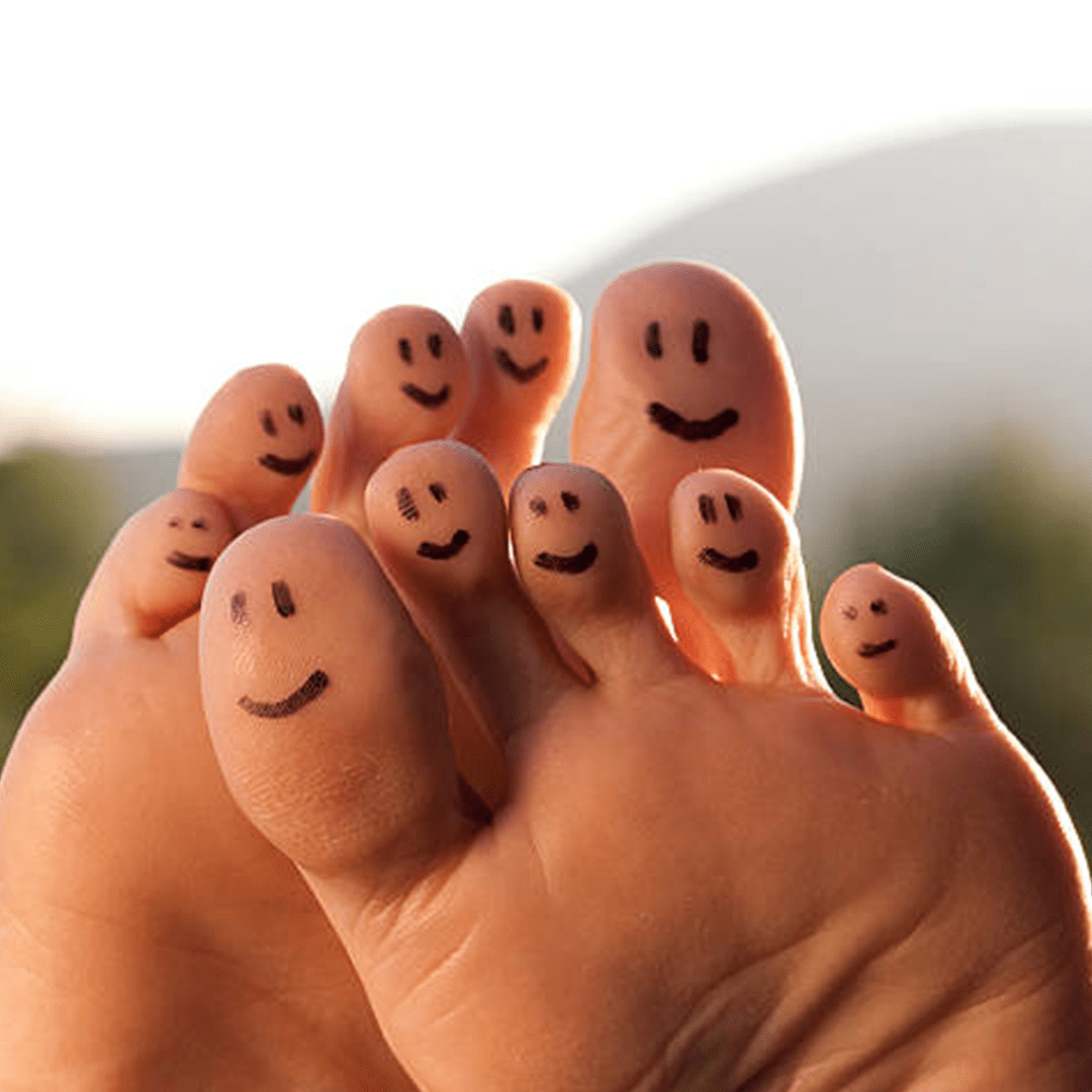 The bottoms of two bare feet with smiley face eyes and smile drawn on each of the ten toes