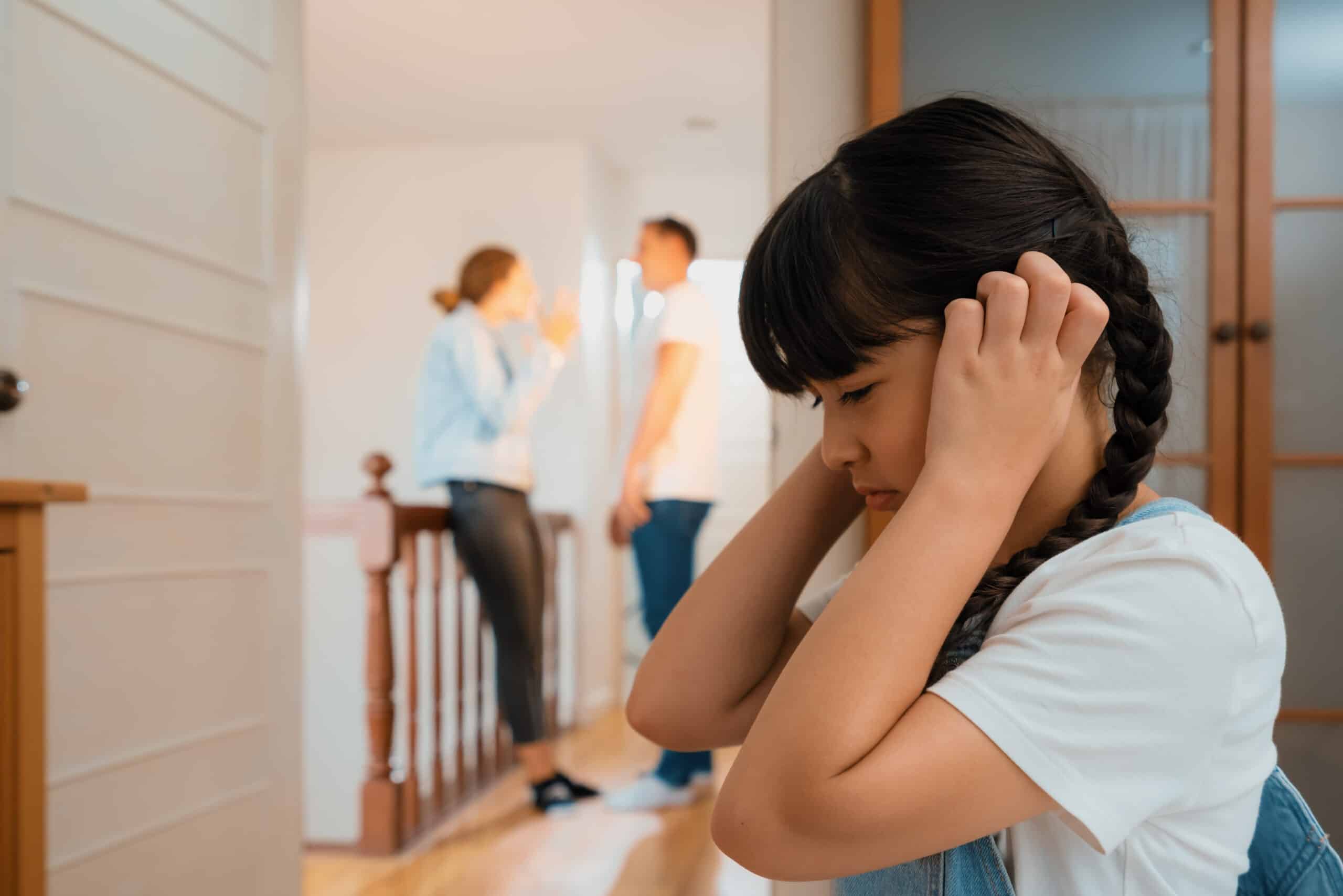 Stressed and unhappy young girl hides from her parents arguing