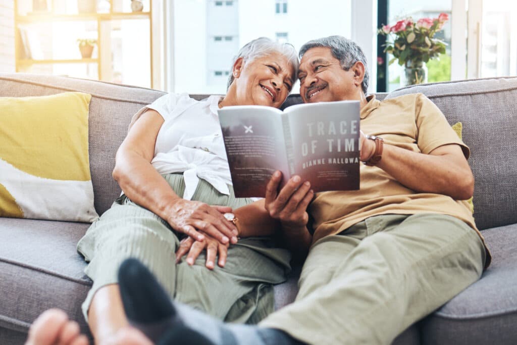 An elderly couple reads together on the couch. Used to promote Senior's Bookclub