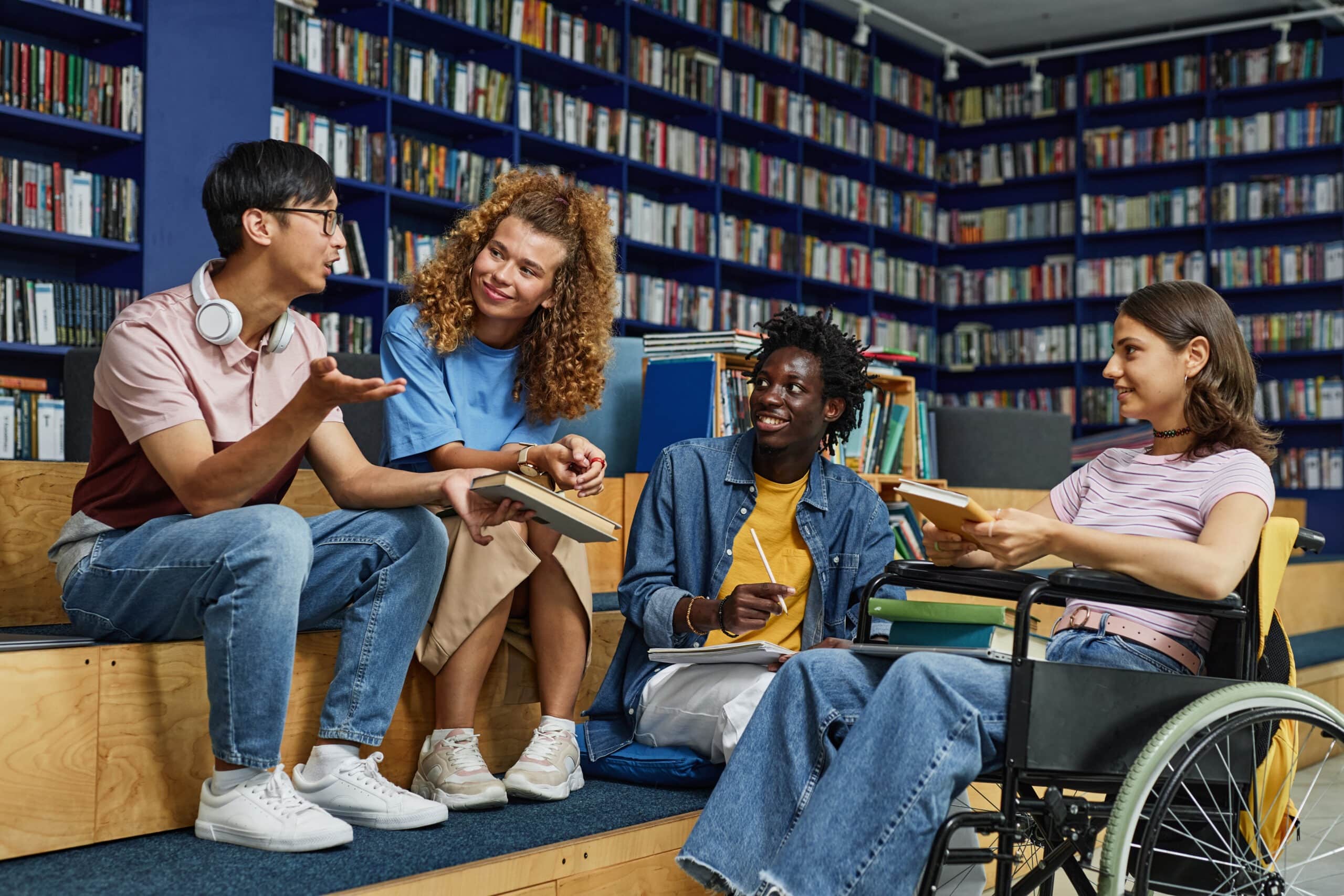 A diverse group of students discuss a book in a library.
