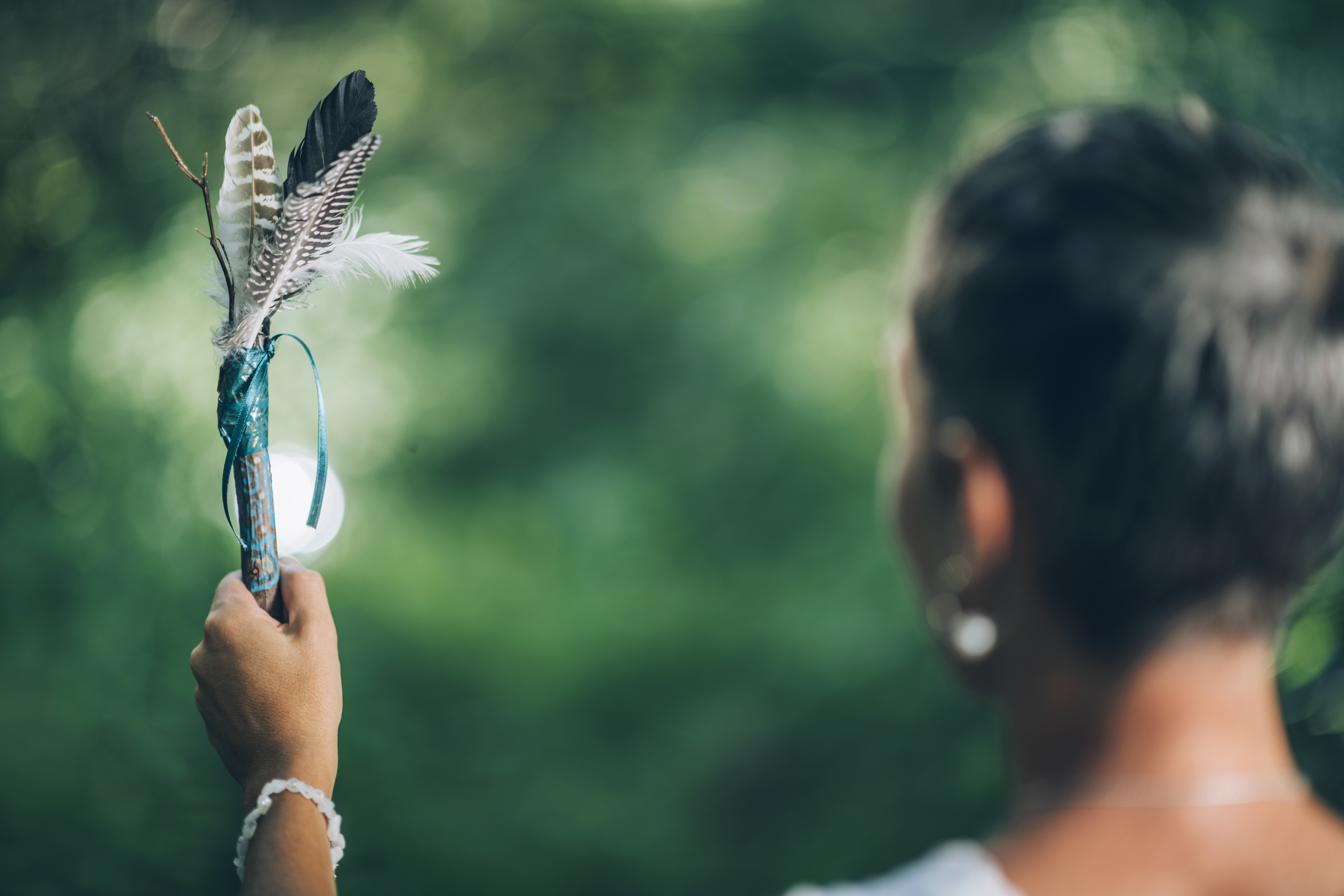 An Indigenous Women from behind holding up feathers.