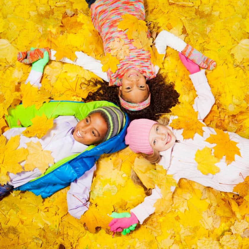 Young Children lay in a pile of leaves