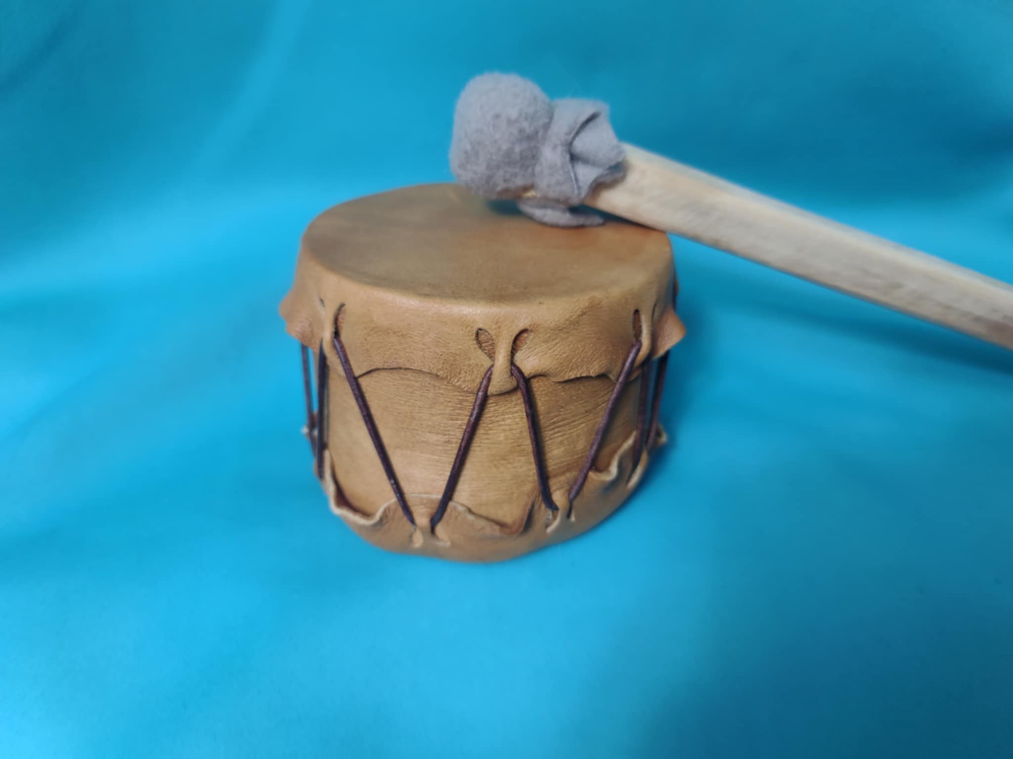 A tiny tot powwow drum against a teal background.