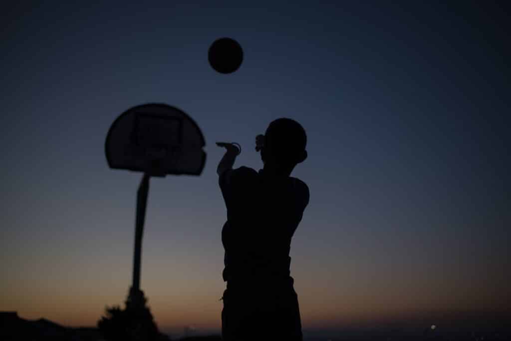A Silhouette of someone shooting a basketball ball towards a hoop at dusk. Used to promote Hoop Nation