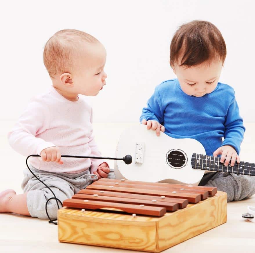 Two babies play with musical instruments. Used to promote Baby and Me