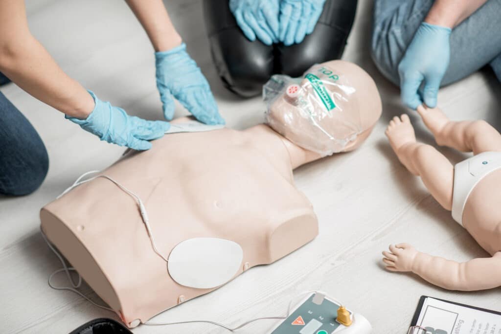 Clinging a contacts on a dummy teaching how to make defibrillation during the first aid and CPR/AED training