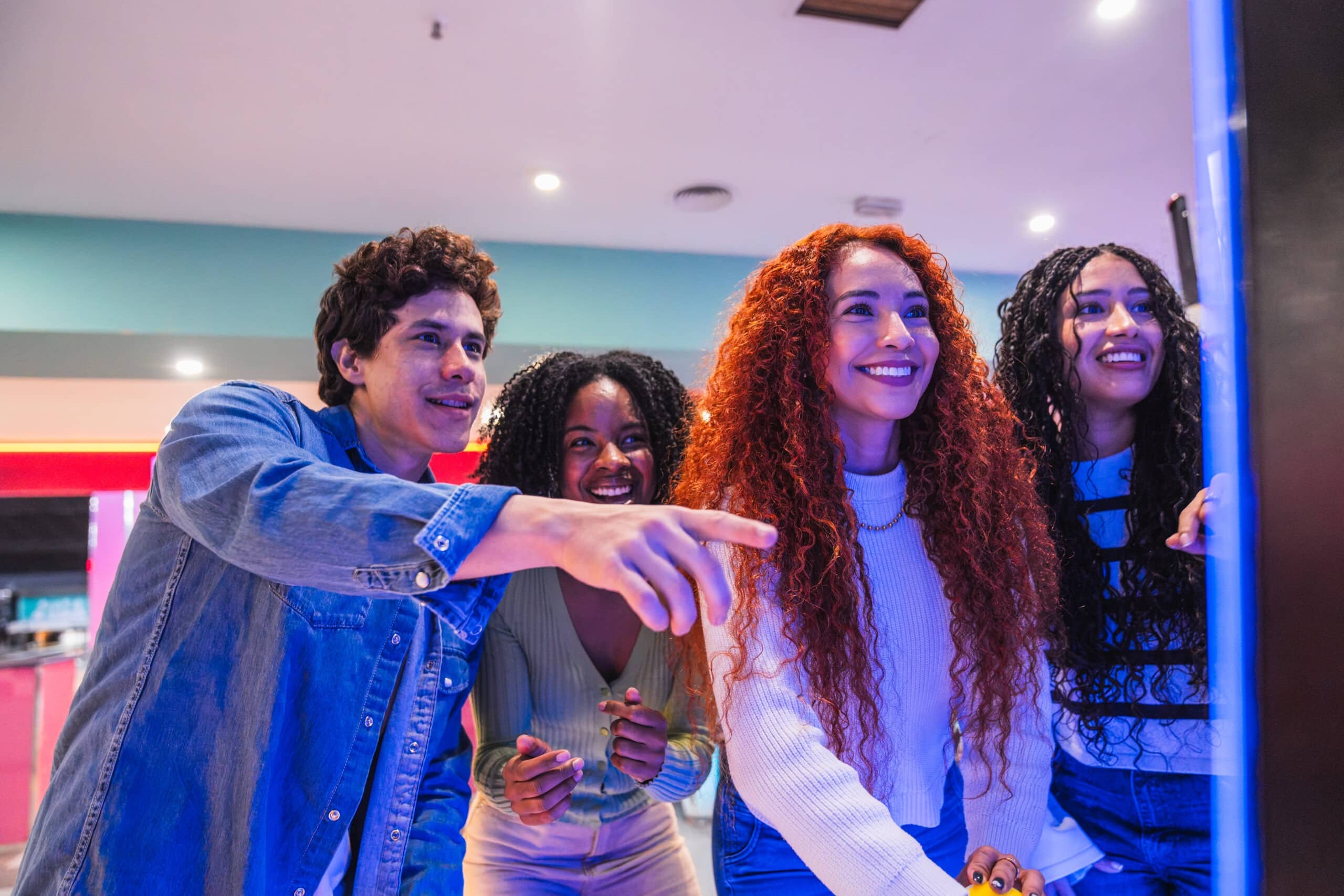 Group of young friends playing arcade video game in bowling alley, enjoying their leisure time together