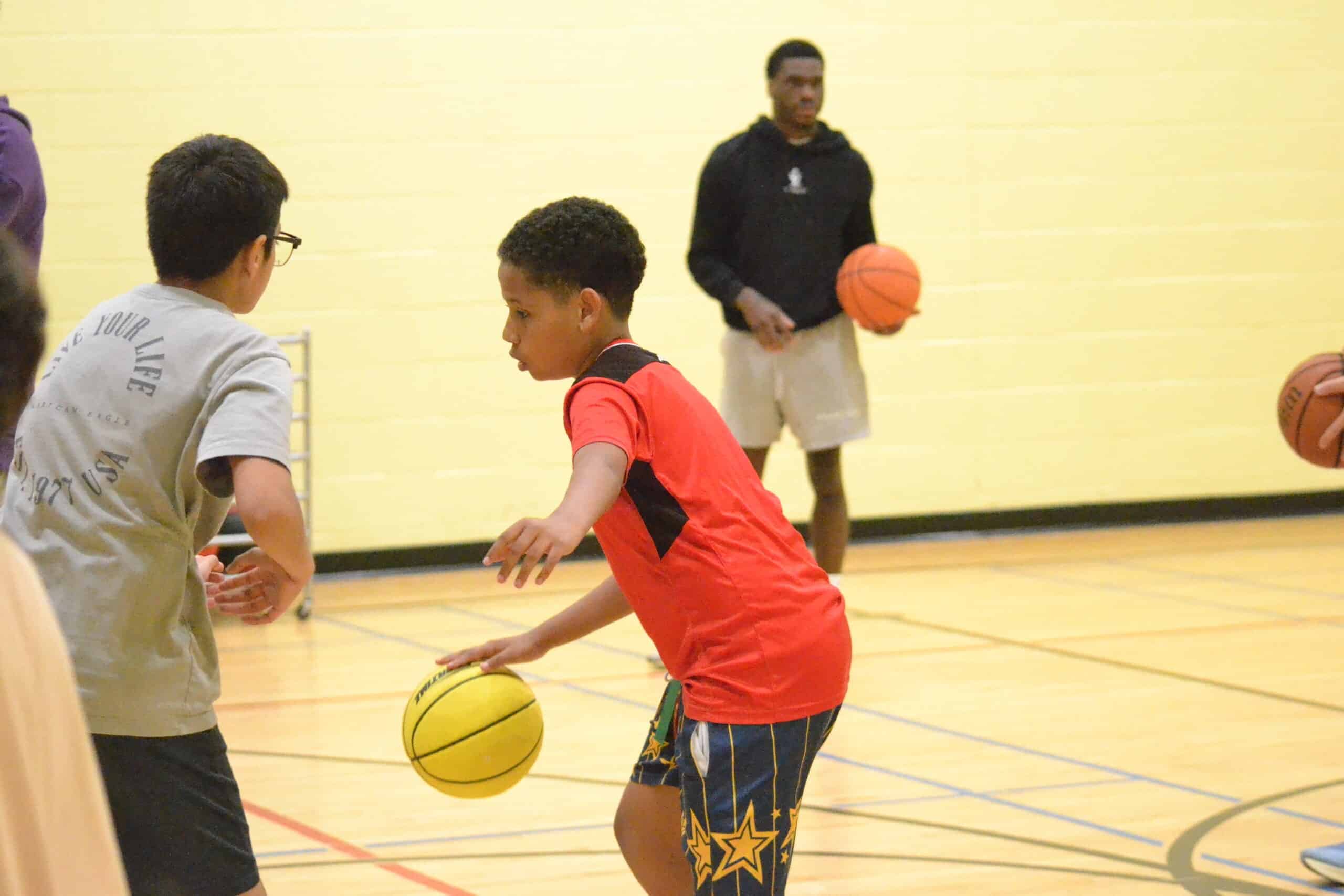 Two children playing basketball in a school gym